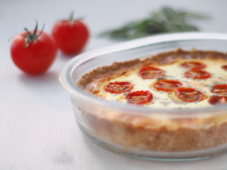 Traditional French quiche pie. Homemade tart with cherry tomatoes, leek and basil leaves. Vegetarian gratin.