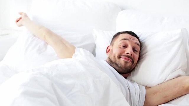 man waking up in bed at home