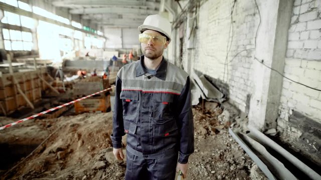The main master at the construction site. A man dressed in a special uniform and with a helmet on his head strolls along the construction site of an industrial facility.