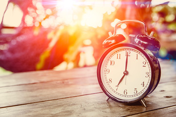 clock on wood table with sunlight effect in the morning times at 7 o'clock.