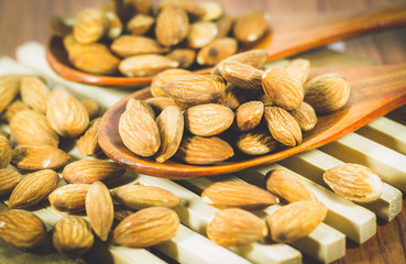 Close up pile of Almonds pour from wood spoon on wood background, Almonds perfect for a diet for a healthy diet and can be used as medicine. concept: diet, fitness, medicine.