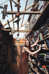 Obraz na płótnie Canvas Young brunette girl standing among books