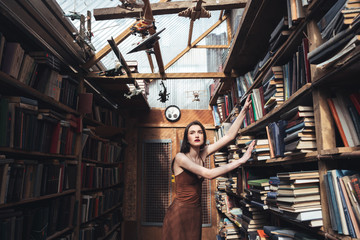 Obraz na płótnie Canvas Young brunette girl standing among books