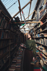 Obraz na płótnie Canvas Girl standing in library with books