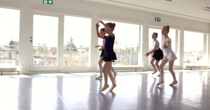 Group of small sporty pretty girls exercising and dancing ballet in the class.