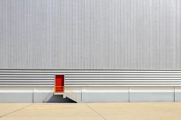 Photo sur Plexiglas Bâtiment industriel La porte de sortie rouge sur le mur en tôle du bâtiment de l& 39 usine.