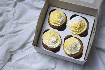 delivery box with delicious freshly baked homemade lemon muffins cupcakes with butter cream for present , copy space