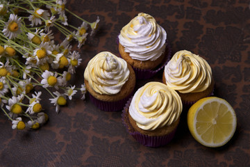 delicious freshly baked homemade lemon muffins cupcakes with butter cream with  bouquet of chamomile flowers , copy space