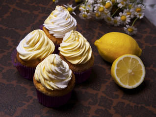 delicious freshly baked homemade lemon muffins cupcakes with butter cream with  bouquet of chamomile flowers , copy space