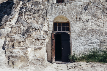 Fototapeta premium Ancient wooden door in the white chalky mountain, the entrance to the hollowed temple inside
