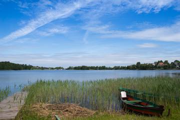 Obraz premium Concept of tranquil country life. Green boat in the lake on sunny summer day in Lithuania, Trakai. Excellent for flyer, post card, advertising, blog, instagram, calendar, notebook, wallpaper