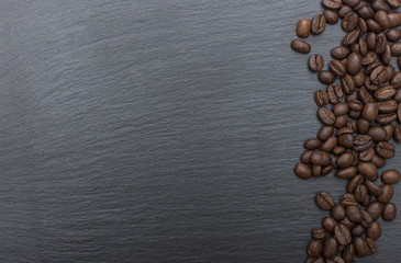 Red rice and olive wood scoop on black background of slate or stone. 