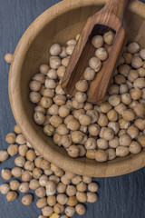 Red rice and olive wood scoop on black background of slate or stone. 