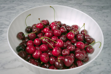 Ripe cherries in a white plastic bowl