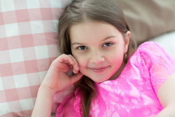 Portrait of pretty girl in pink dress in bed