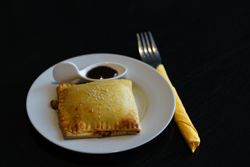 Delicious pork belly pie with sauce in white plate on wood background