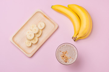 Fresh made banana smoothie in a glass on pink background
