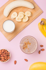Fresh made banana smoothie in a glass on pink background