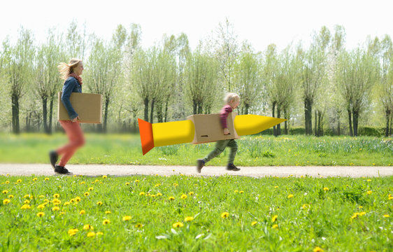 Mid adult woman running with son in cardboard rocket