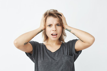 Displeased young pretty girl looking at camera ashamed holding head over white background.