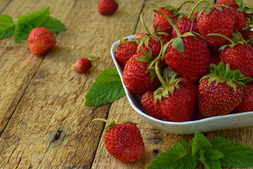 Organic fresh strawberry from garden in bowl on wooden background. Copy space for your text