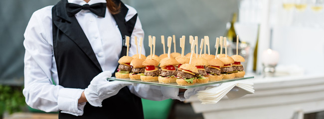 Catering service. Waiter carrying a tray of appetizers. Outdoor party with finger food, mini...