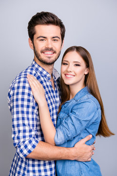 True love, trust, friendship, happiness. Two young cute lovers are looking at the camera and smile, wearing casual outfits, hugging gently on the pure background