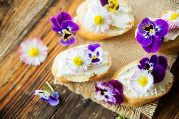 Fototapeta na wymiar Sandwich with herb and edible flowers butter on marble cutting board. Healthy food.