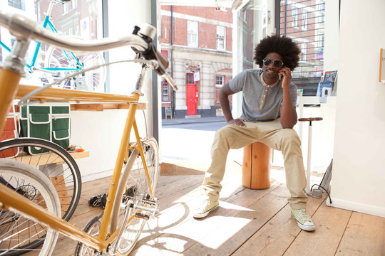 Mature man on cell phone in bicycle shop