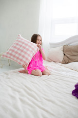 Obraz na płótnie Canvas Pretty girl in pink dress in bed with cushin