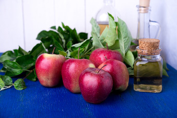 Apple cider vinegar. Three glass bottle on blue background. Red apples.