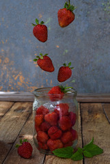 Composition of flying strawberry in jar. Cooking preparation compote or jam. Homemade conservation with organic fresh berry for the winter. Fruit dessert. Confectionery.