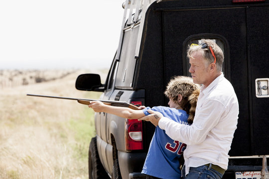 Father teaching son with rifle, Texas, USA