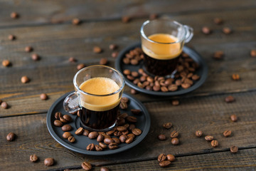 Two cups of espresso and coffee beans on a wooden table