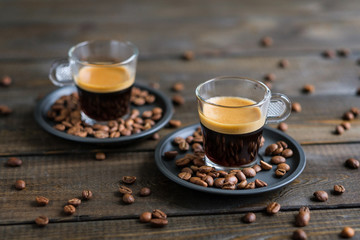 Two cups of espresso and coffee beans on a wooden table