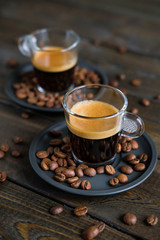 Two cups of espresso and coffee beans on a wooden table