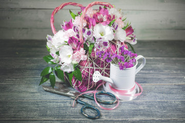 Bouquet of flowers in original gift basket on a vintage wooden table