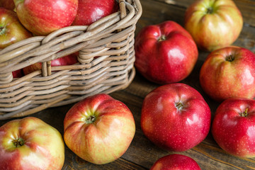 basket with red ripe apples on a brown wooden table