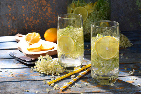 Elderberry flowers and lemon drink. Refreshment healthy elder juice. Glass of elderflower lemonade on wooden rustic board. Alternative medicine and therapy