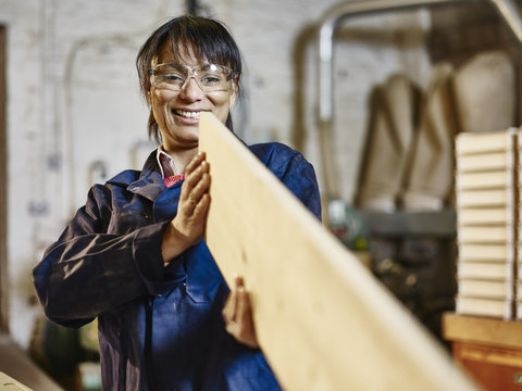 Woman examining straightness of wood plank in printing workshop