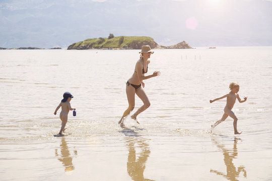 Mature woman running in sea with two sons, Lopar, Rab Island, Croatia