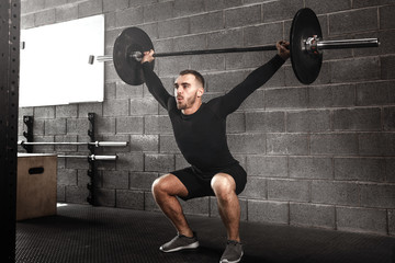 Young man lifting barbells at gym