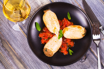 Squid stuffed with meat and vegetables, garnished with meant on black plate. View from above, top studio shot