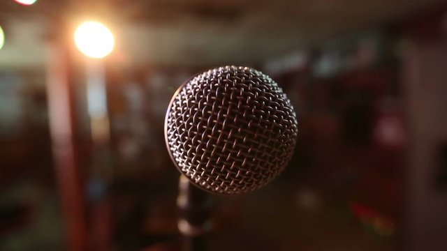 View of microphone on stage facing empty auditorium. Colorful spotlights