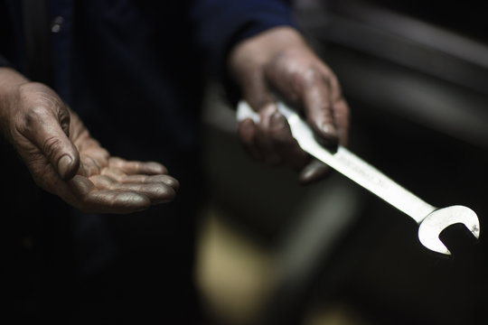 Oily hands of male weaver fixing old weaving machine in textile mill