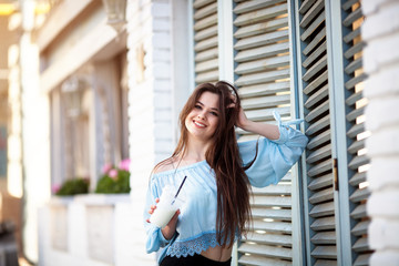 Portrait beautiful girl with long hair in a casual outfit posing at the Italian cafe . Beautiful brunette Keeps coffee.