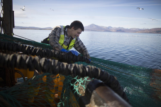 Fisherman releasing net into sea, Isle of Skye, Scotland