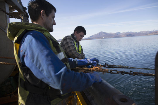 Fisherman releasing net into sea, Isle of Skye, Scotland