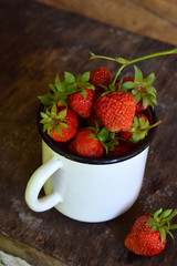Organic fresh strawberry from garden in cup on wooden background. Copy space for your text