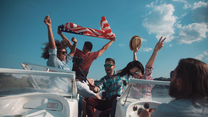 Group of laughing friends having fun on boat and taking selfie.